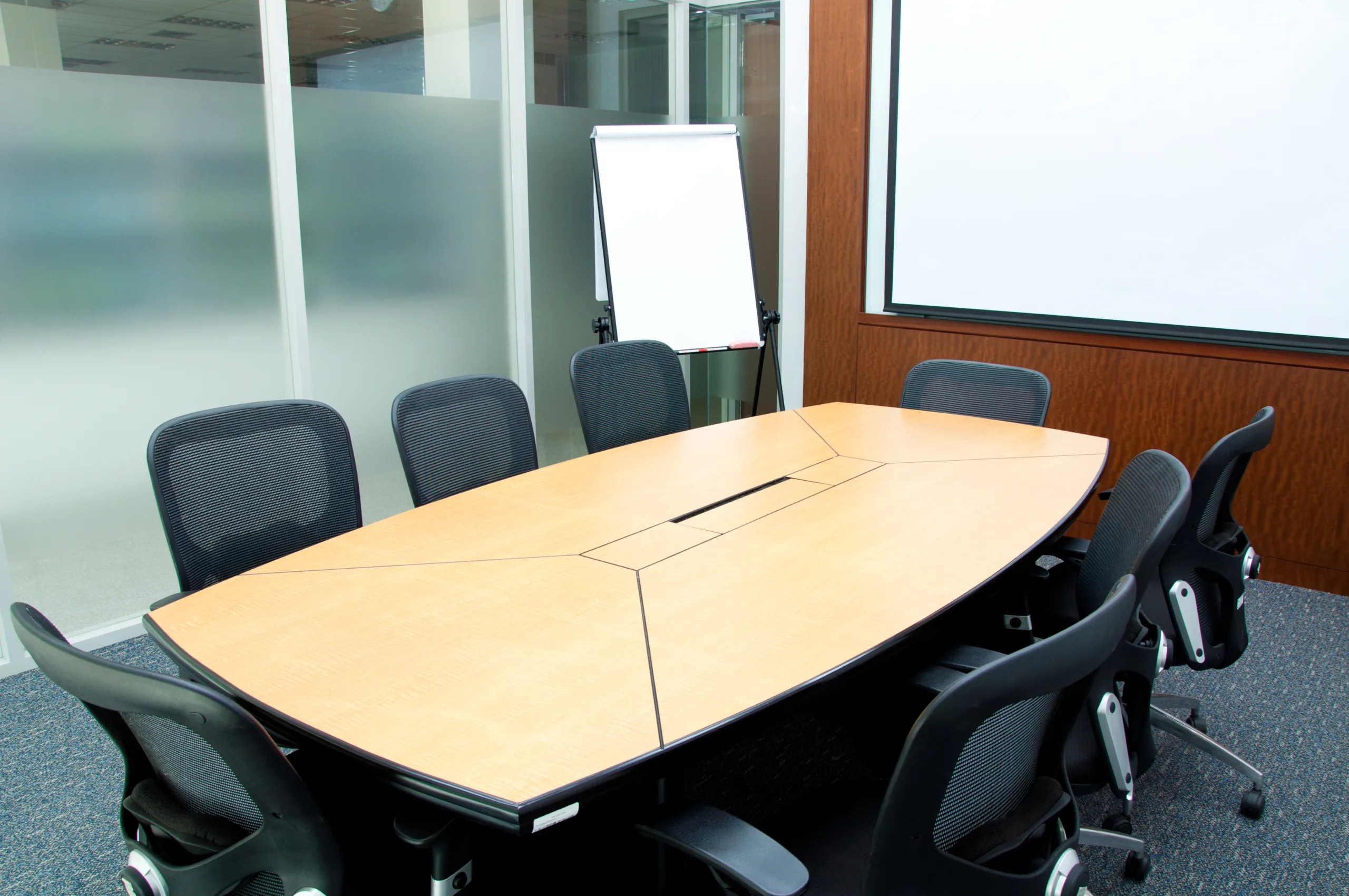 A conference room with a wooden table and chairs.